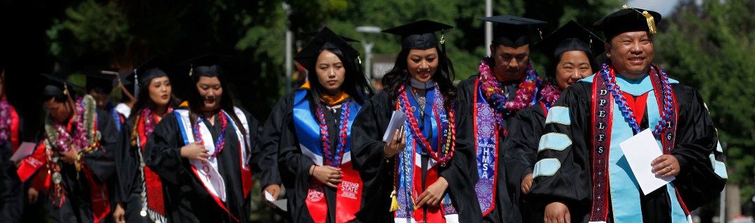 Students in graduation gowns walking and smiles on their face