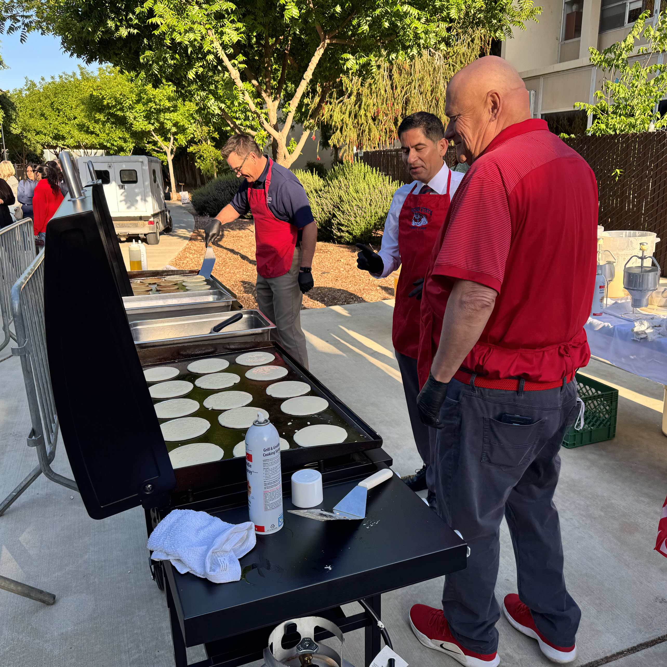 Men flipping pancakes at griddles